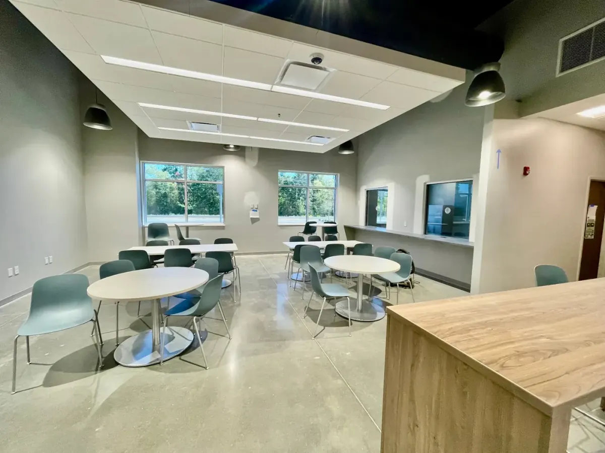 Bright break room with round tables, chairs, and clean polished floors