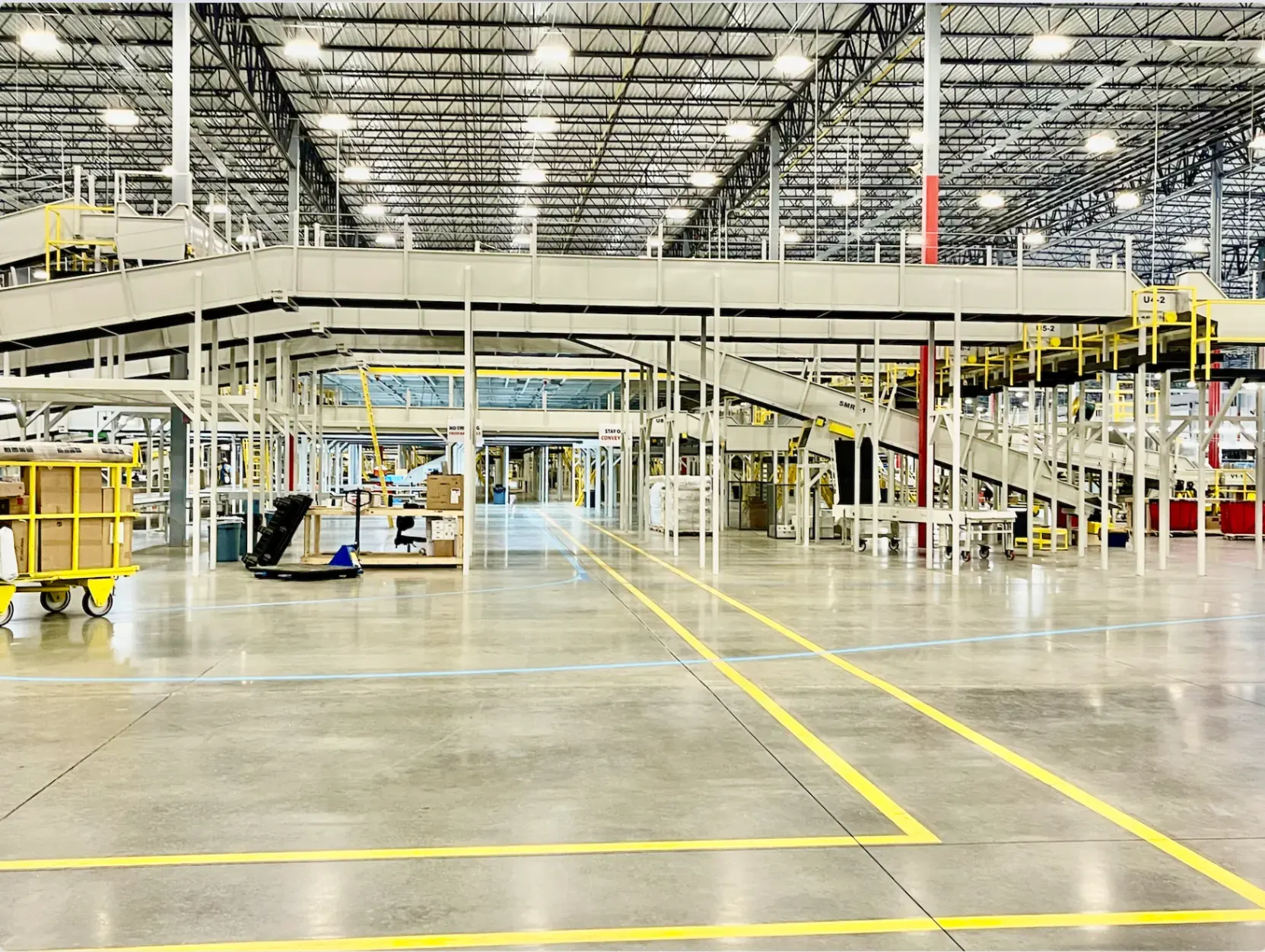 Polished concrete floor with bright yellow safety lanes inside a large distribution warehouse