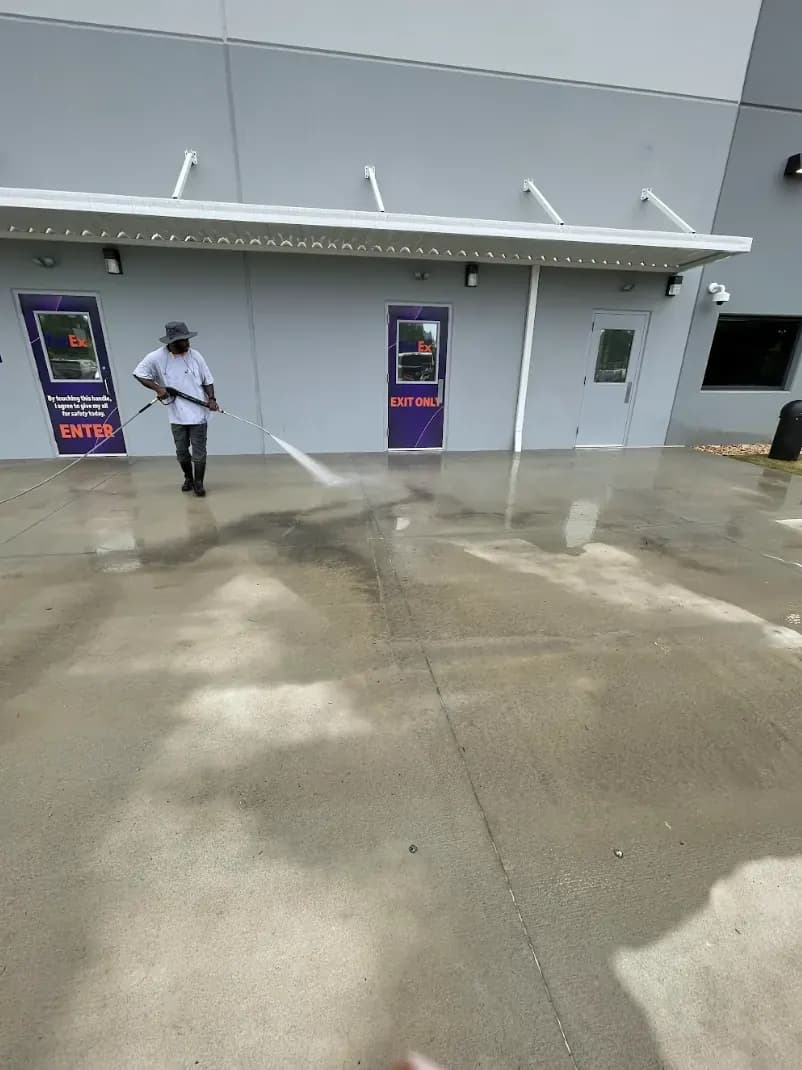 Crew member pressure washing concrete outside a building entrance